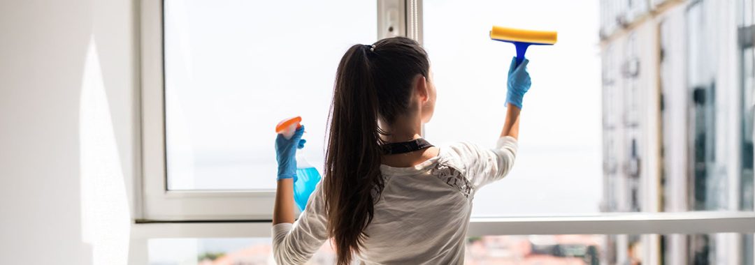 Person cleaning a uPVC window from the inside with blue gloves in a Leicester home